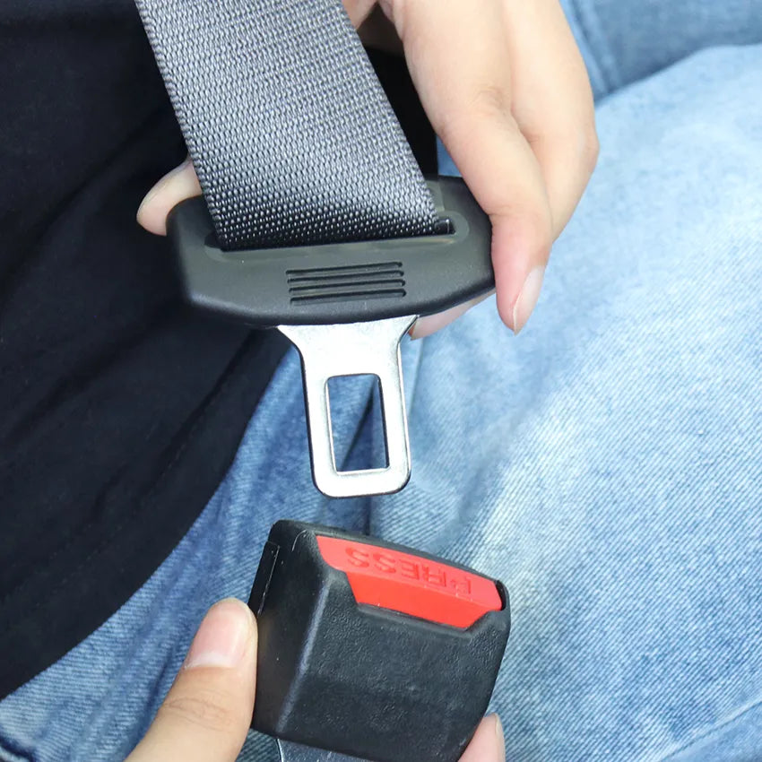 A person in jeans holds a seat belt tongue above the insert, about to click it in 4