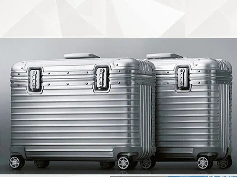 Two silver ribbed aluminium cases side by side against a grey studio backdrop, showing locks and top handles 4