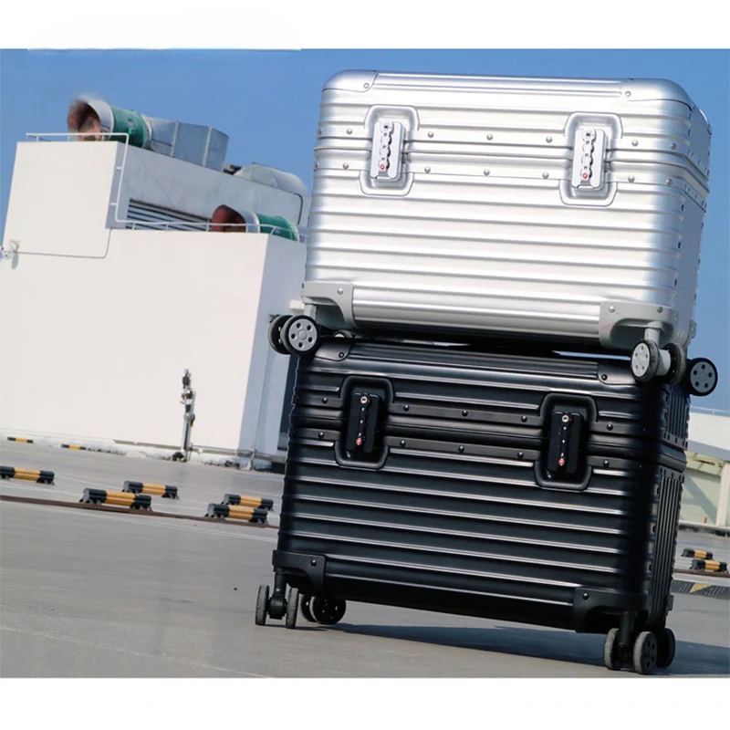 Silver case stacked on a black one outdoors, both showing their ribbed shells, twin locks and wheels 2