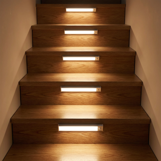 Row of light bars mounted on the risers of a wooden staircase, each casting a warm glow onto the steps. 2