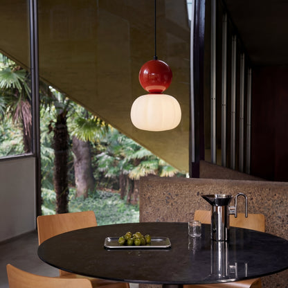 Single pendant with a red cap hanging over a round dark dining table 3