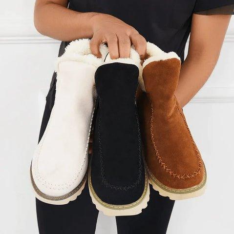 Three fleece-lined ankle boots in cream, black and tan held together in a model's hands, showing the colour options. 7
