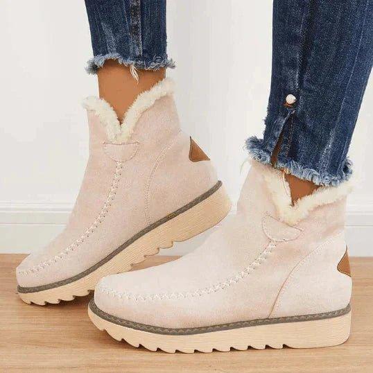 Pale beige ankle boots with soft fleece collar and brown heel patch, worn by a model in frayed-hem jeans, side view. 3