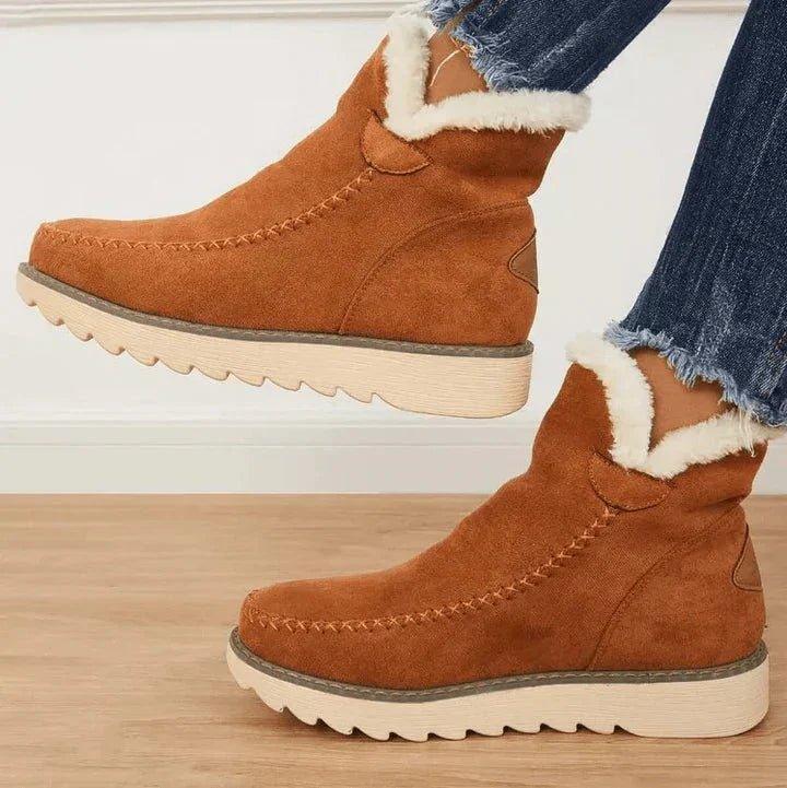 Tan brown suede-look ankle boots with fluffy white lining and ridged cream sole, side view on a model wearing frayed jeans. 2