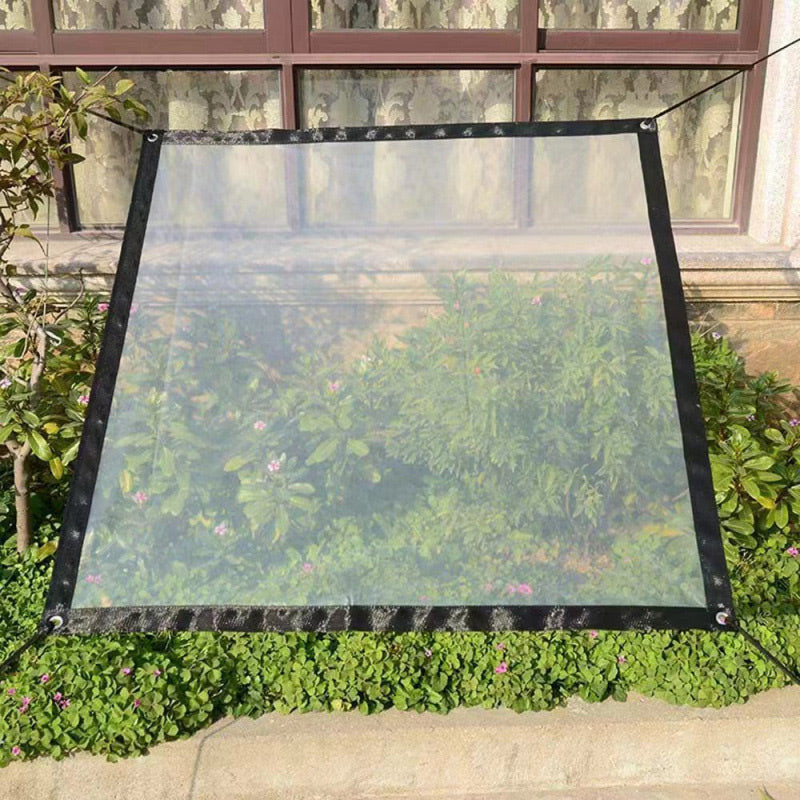 Clear tarp with black edging stretched taut on cords over a flowerbed in front of a window. 7