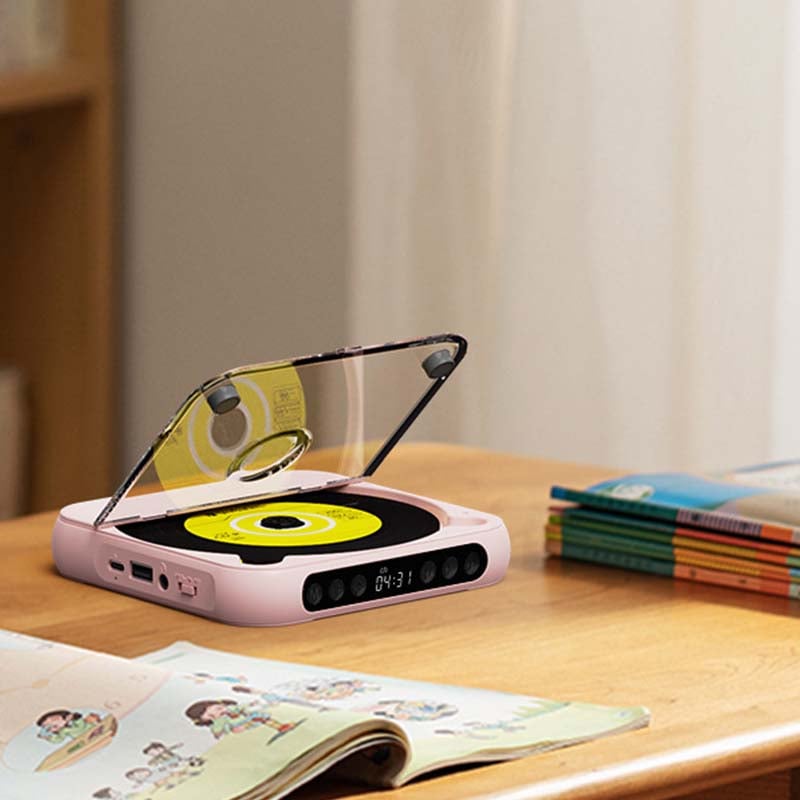 Pink player with its lid open and a yellow disc on a desk beside a stack of children's books. 10