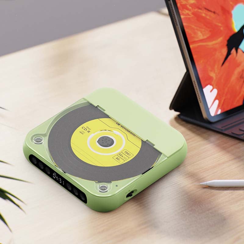 Green player with a yellow disc visible under its lid, on a desk beside a tablet in a case and a stylus. 12