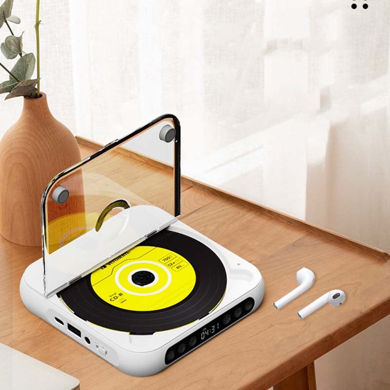 White player with raised lid and yellow disc on a wooden desk, with wireless earbuds and a vase nearby. 8