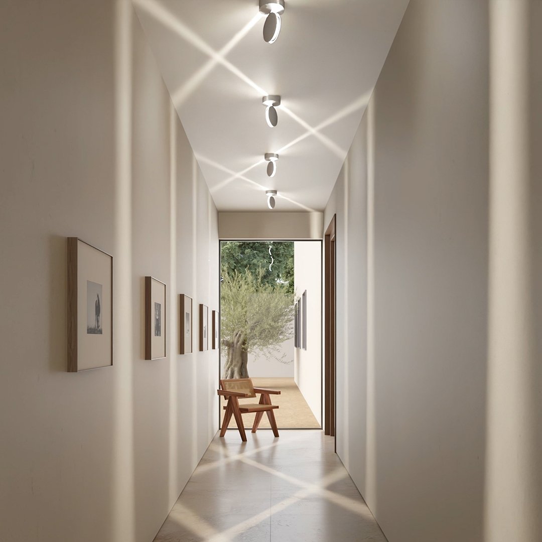 Ceiling lights in a bright hallway with heads turned to create criss-crossing diagonal beams over the ceiling and floor. 7