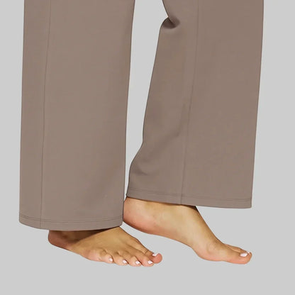 Close-up of the taupe trouser hems and stitched seams, worn barefoot, showing the straight, wide leg opening. 5