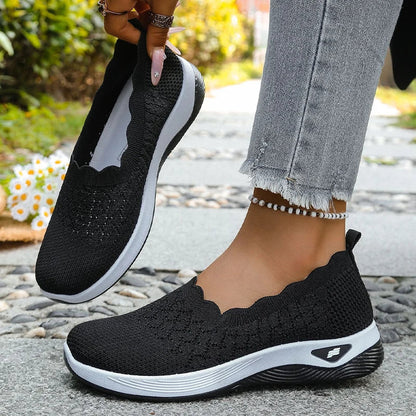Black knit slip-ons with white midsole, one held up to show the lining and one worn on foot 13