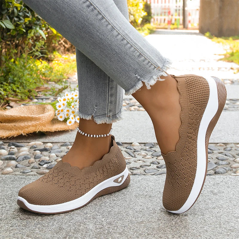 Brown knit slip-ons with white midsole worn mid-step with frayed jeans, daisies and straw hat in the background 20