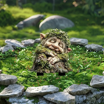 Sleeping troll on a mossy stump with two black stakes visible beneath, set on a mossy lawn ringed with flat stones. 18