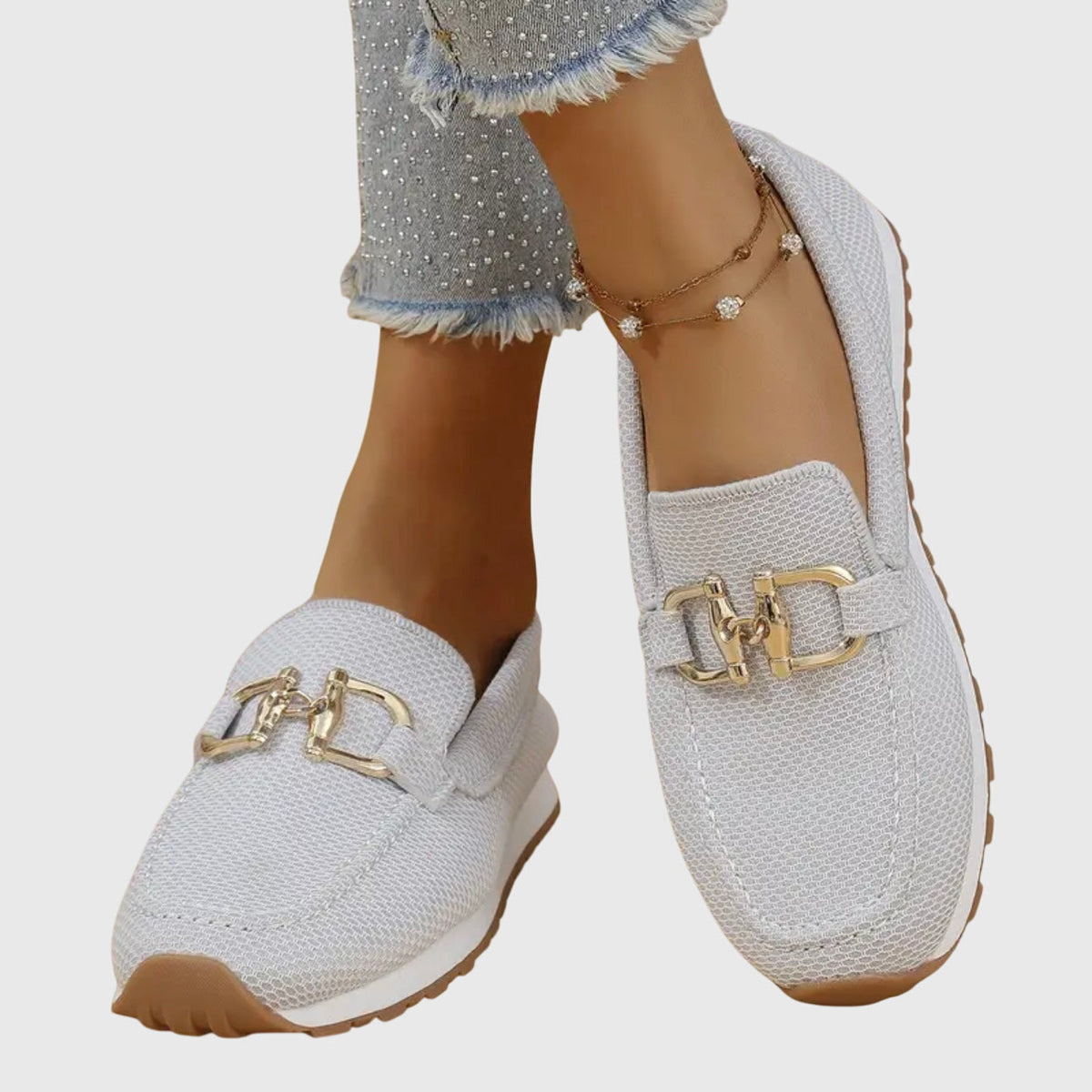 Light grey mesh loafers worn with feet crossed, showing the gold buckle details from above 6
