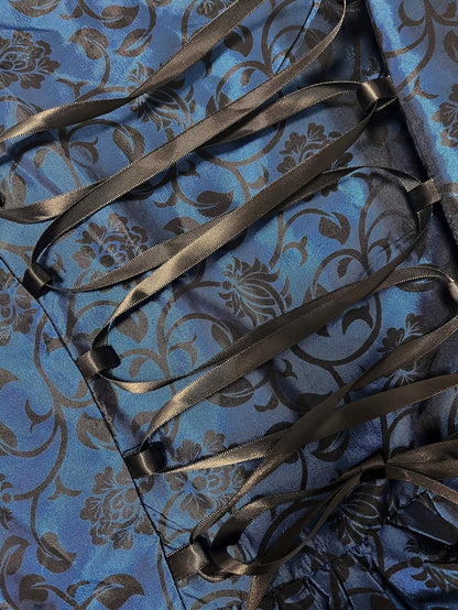 Close-up of the blue floral brocade fabric with black satin ribbon lacing and bow at the back of the gown. 5