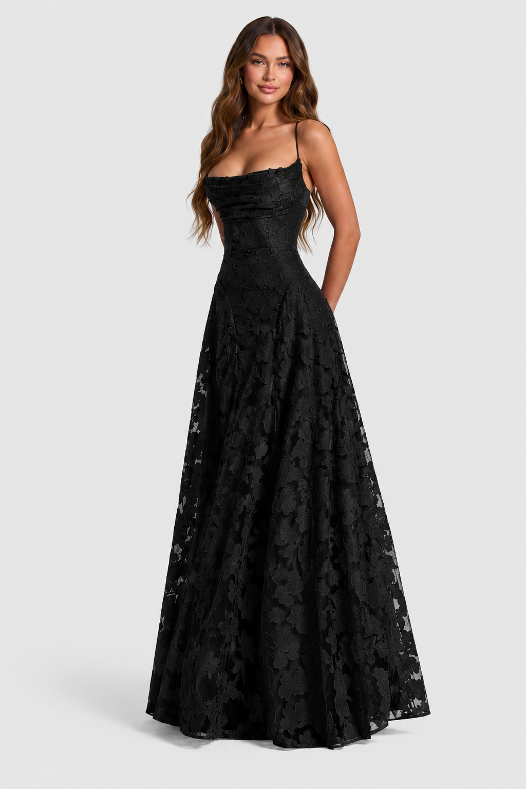 Model smiling in a black floral lace gown with draped neckline, thin straps and a full A-line skirt. 10