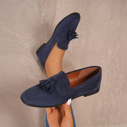 Navy tasselled loafers seen from above, one held in a hand to show the tan lining 5