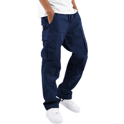 Model wearing navy blue cargo trousers with a white t-shirt and white trainers, hand in pocket, angled side view. 6