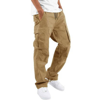 Model wearing sandy tan cargo trousers with a white t-shirt and white trainers, hand in pocket, angled side view. 7