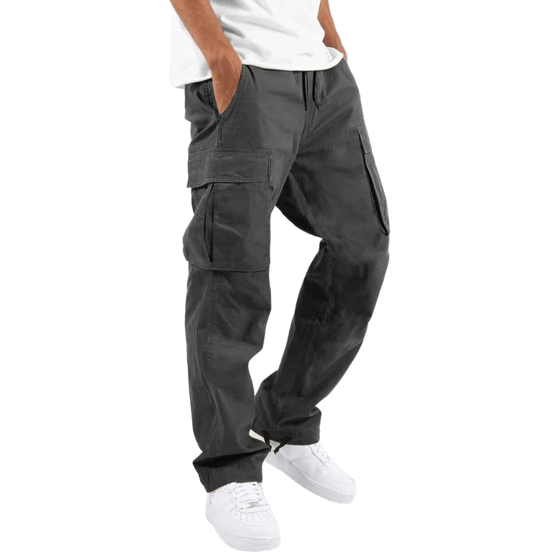 Model wearing dark grey cargo trousers with a white t-shirt and white trainers, hand in pocket, angled side view. 8
