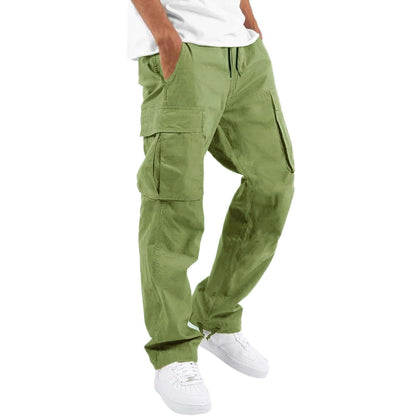 Model wearing light olive green cargo trousers with a white t-shirt and white trainers, hand in pocket, angled side view. 9