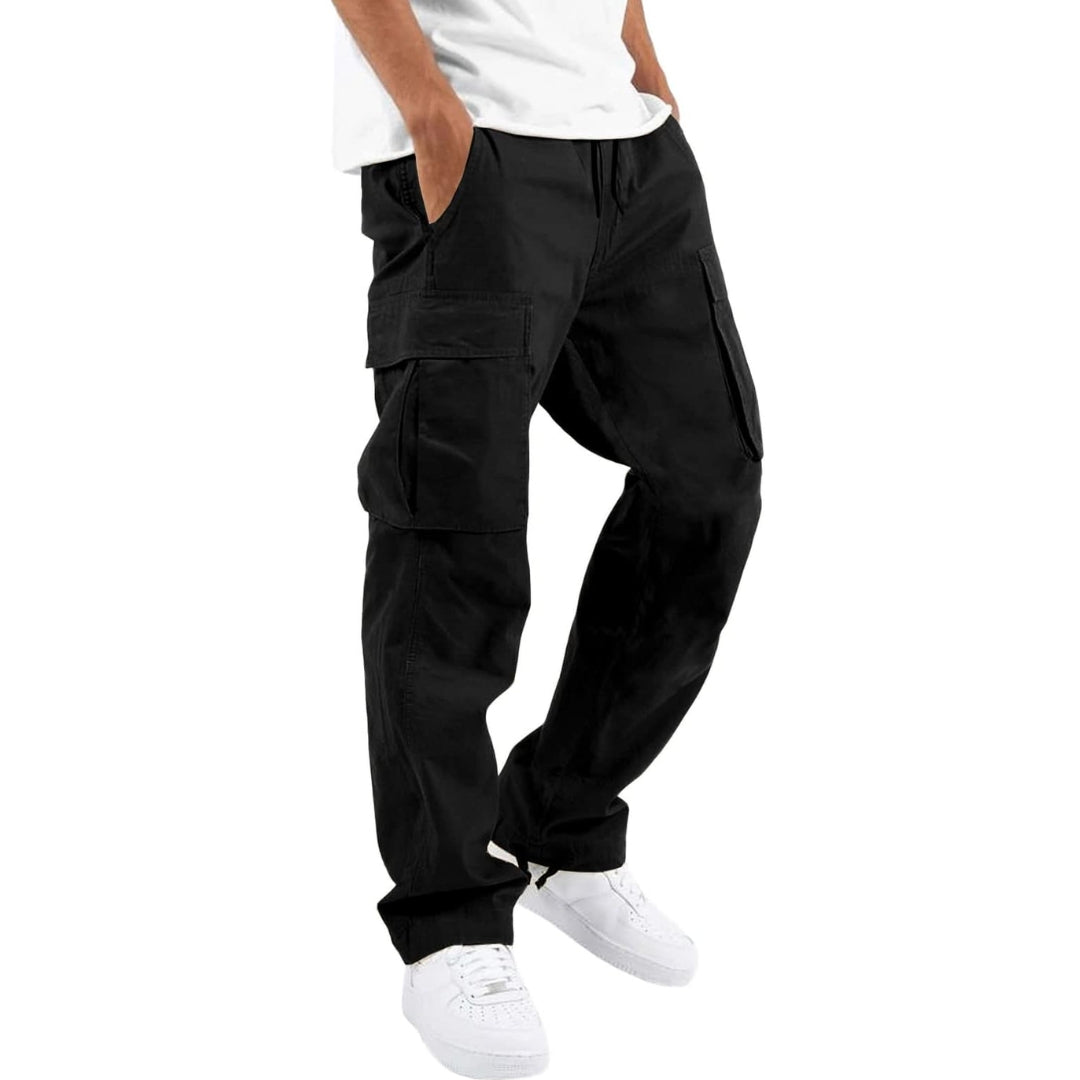 Model wearing black cargo trousers with a white t-shirt and white trainers, hand in pocket, angled side view. 4