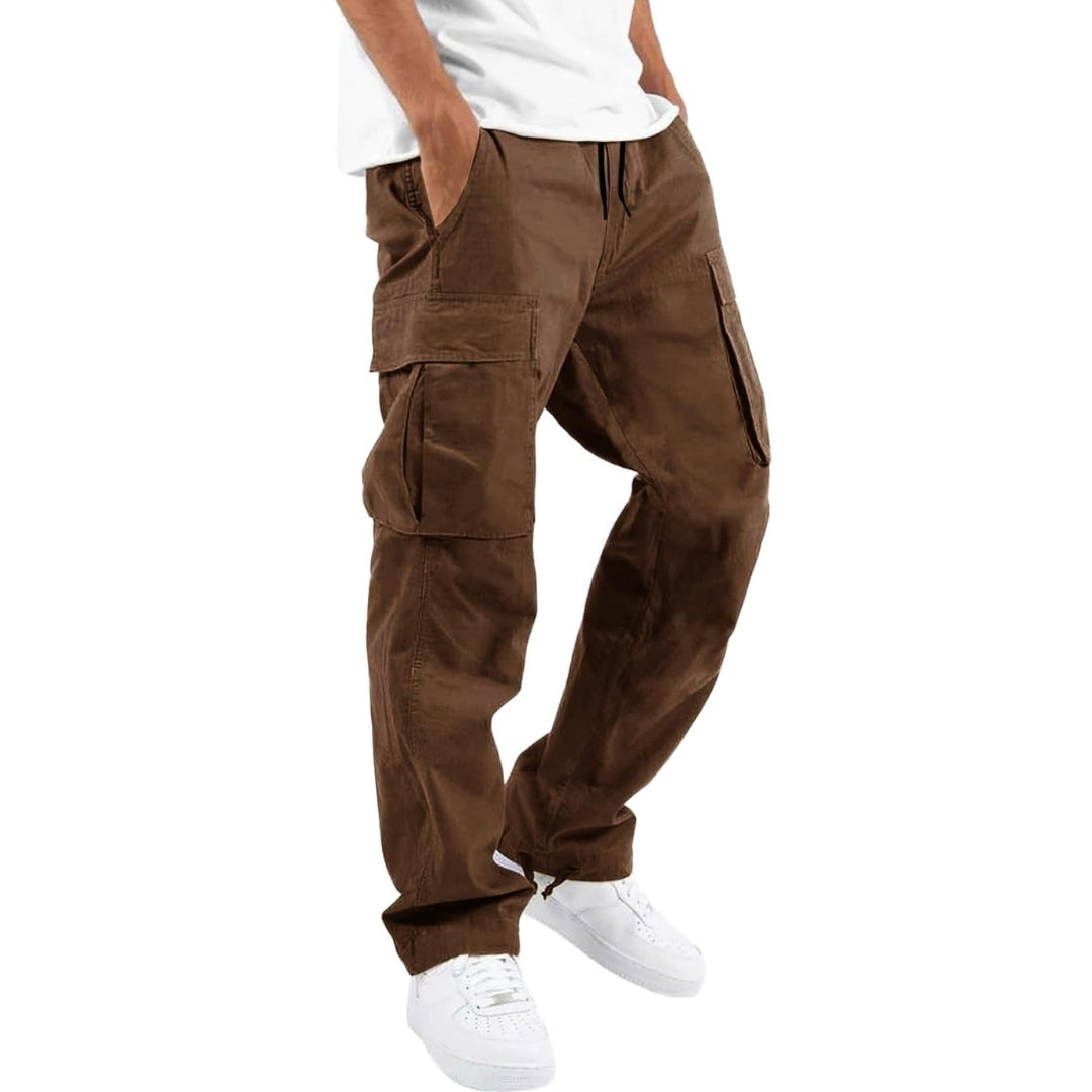 Model wearing brown cargo trousers with a white t-shirt and white trainers, hand in pocket, angled side view. 5