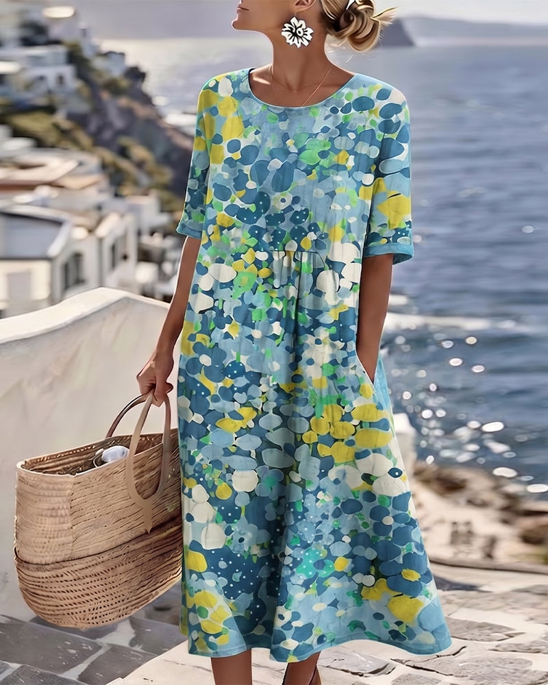 Model wearing the blue, yellow and green floral midi dress, carrying a woven basket by the sea 9
