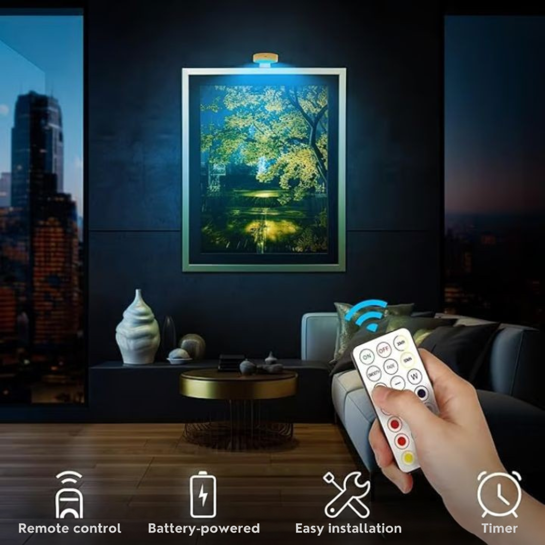 Hand holding the remote control towards a light above a framed tree picture in a dark living room 5