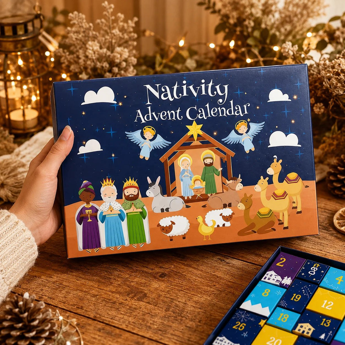 Hand holding the illustrated navy box lid with nativity scene artwork, open tray of numbered doors beside it 4