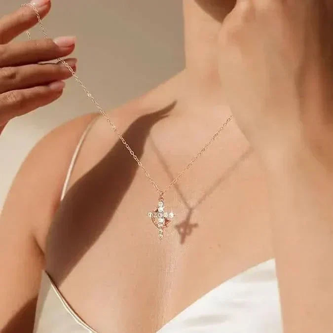 Close view of a model lifting the fine chain, the crystal cross pendant resting at her collarbone in soft sunlight. 3