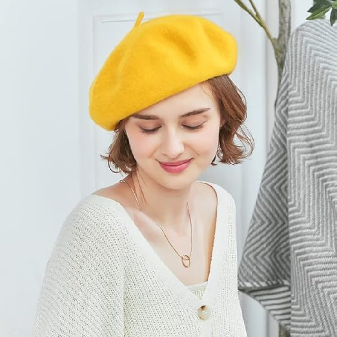 Smiling woman wearing a yellow beret with a cream knit cardigan and a gold necklace 16