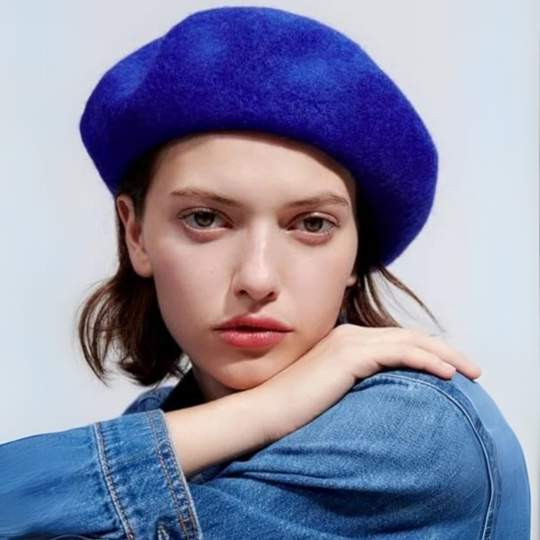 Woman in a bright blue beret and a denim jacket, resting her chin on her arm 19