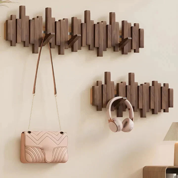 Two dark wooden racks on a cream wall, one holding a pink quilted bag, the other pink headphones 9