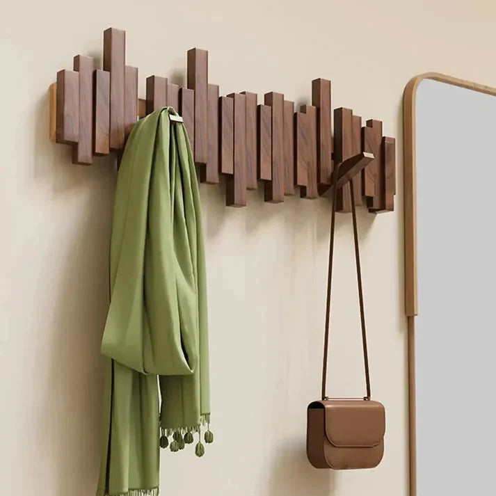 Dark walnut-toned rack on a cream wall with a green scarf and a tan handbag hanging 1