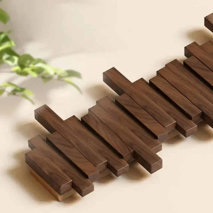Close-up of the staggered dark wooden slats lying flat, with a green plant blurred beside 3