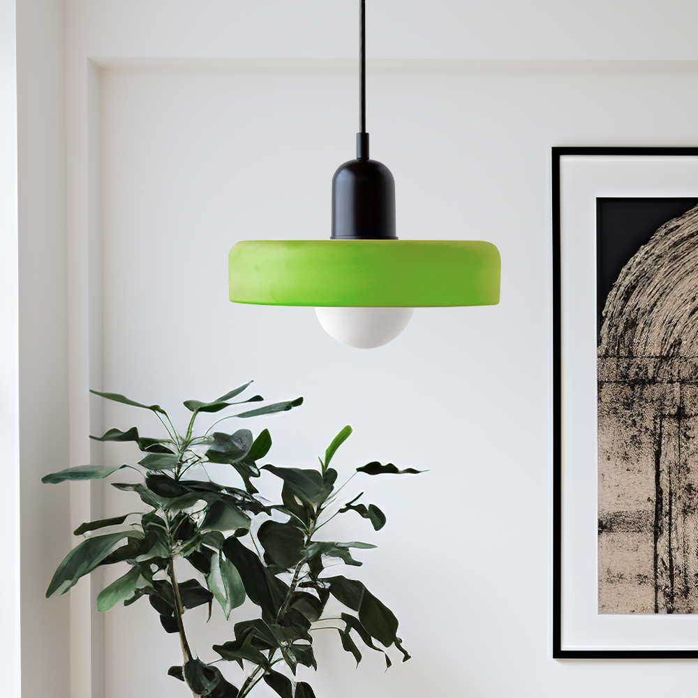 Lime green disc pendant with black dome cap hanging beside a leafy plant and framed artwork 52