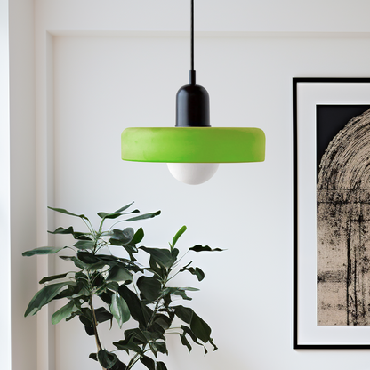 Lime green disc pendant with black dome cap hanging beside a leafy plant and framed artwork 52