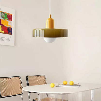 Olive glass pendant lamp with a yellow cap above a white table with lemons and rattan chairs 18