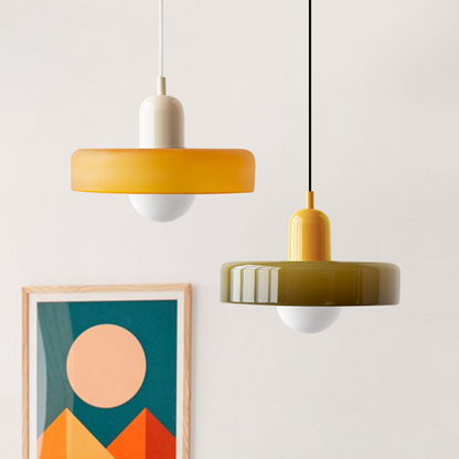 Two pendants hanging together, one amber with a cream cap, one olive with a yellow cap, above framed art 27