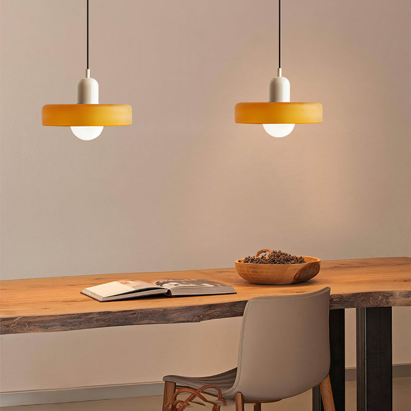 Two lit yellow glass pendants with cream caps above a live-edge wooden desk with an open book 33