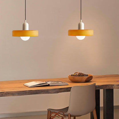 Two amber glass pendants with cream caps hanging above a live-edge wooden desk with an open book 33