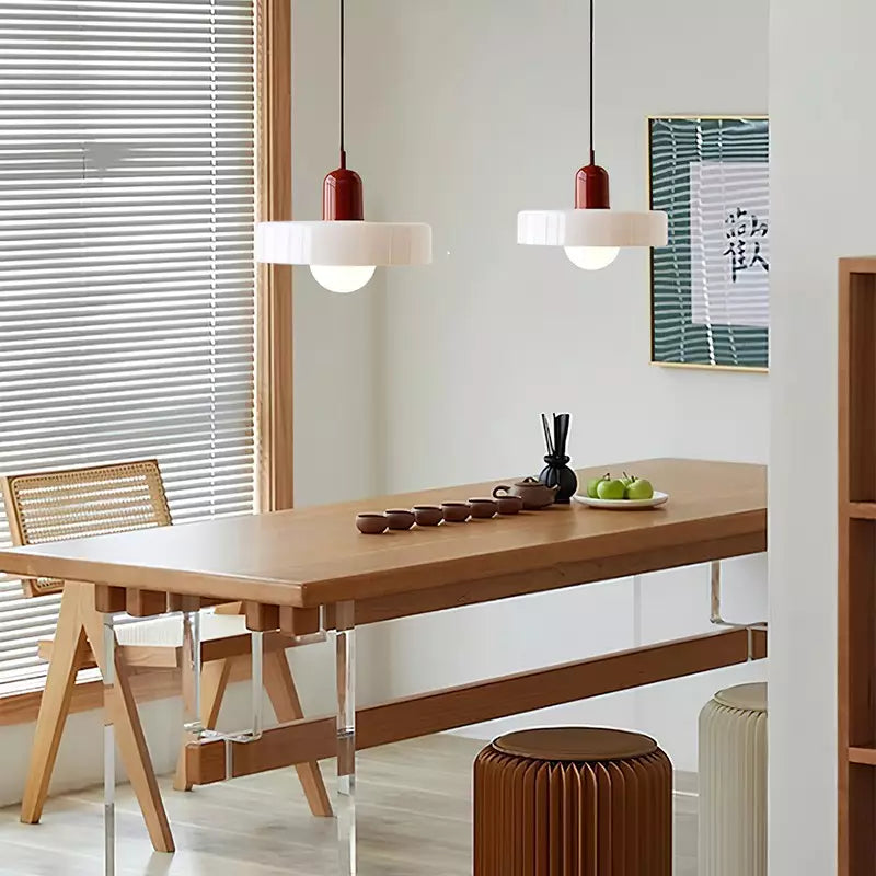 Two white glass pendants with red caps above a long wooden table with tea cups and green apples 36