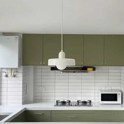 White pendant hanging above a kitchen worktop, with green cabinets and white tiled splashback behind 48