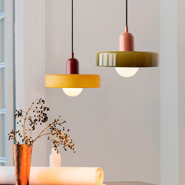 Amber pendant lamp with red cap beside an olive one with coral cap, near a vase of dried stems 7