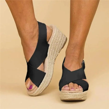Front-angled view of black crossover-strap wedge sandals, highlighting the open toe and raised braided platform 8