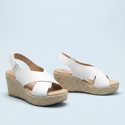 Pair of white crossover wedges against a pale blue backdrop, with heel straps and rope soles 14