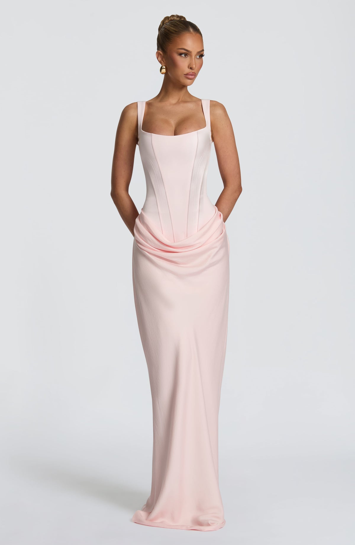 Model in the pale pink corset maxi dress with hands tucked behind, looking to the side 13