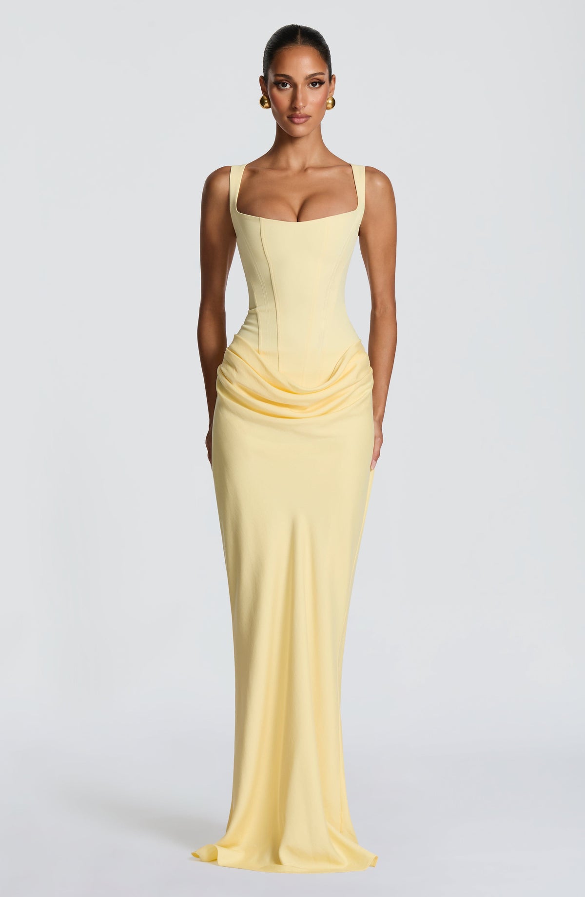 Model wearing the pale yellow corset maxi dress, standing front-on with gold ball earrings 9