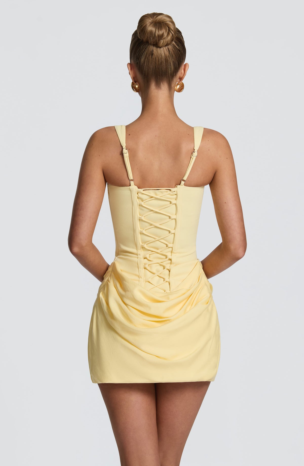 Back view of the pale yellow dress, showing the lace-up corset back, adjustable straps and draped skirt. 23